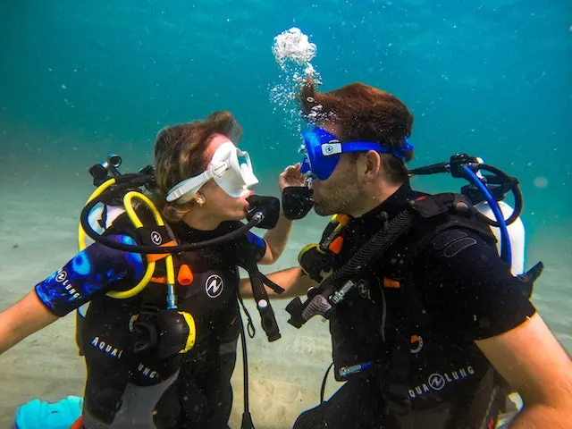 Two divers wearing diving gear while swimming underwater